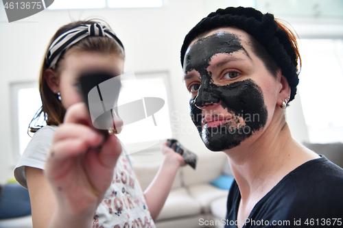 Image of mother and daughter at home making facial mask beauty treatment