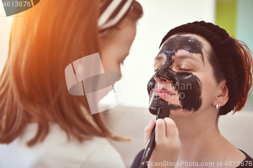 Image of mother and daughter at home making facial mask beauty treatment