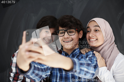 Image of group of arab teens taking selfie photo on smart phone