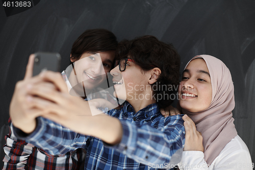 Image of group of arab teens taking selfie photo on smart phone