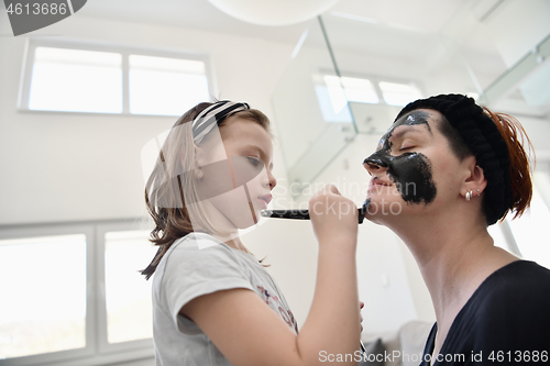 Image of mother and daughter at home making facial mask beauty treatment