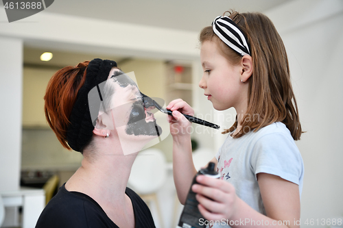 Image of mother and daughter at home making facial mask beauty treatment