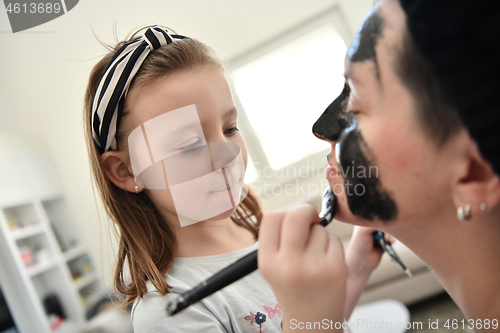 Image of mother and daughter at home making facial mask beauty treatment