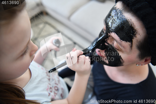 Image of mother and daughter at home making facial mask beauty treatment