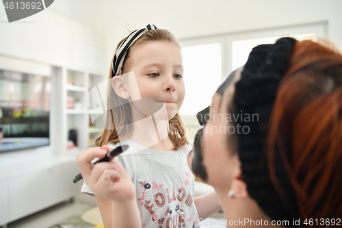 Image of mother and daughter at home making facial mask beauty treatment