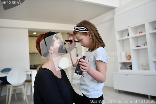 Image of mother and daughter at home making facial mask beauty treatment