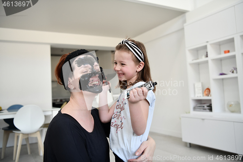 Image of mother and daughter at home making facial mask beauty treatment