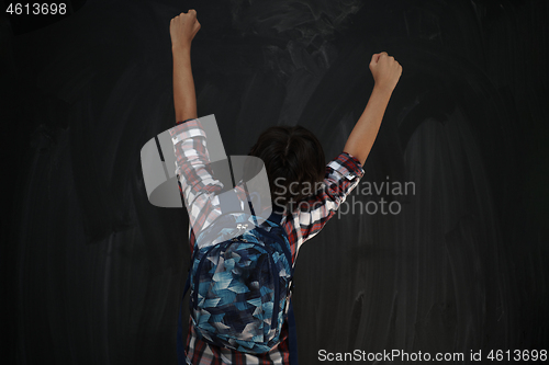 Image of happy arab teenager  celebrating against black chalkboard