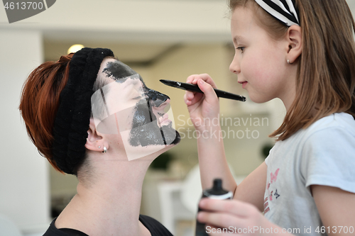 Image of mother and daughter at home making facial mask beauty treatment