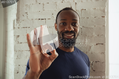 Image of African-american musician isolared on white brick wall background, cheerful and happy