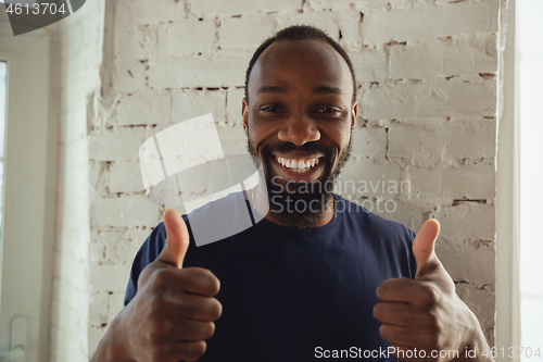 Image of African-american musician isolared on white brick wall background, cheerful and happy