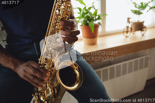 Image of African-american musician playing saxophone during online concert at home isolated and quarantined, close up