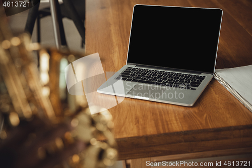 Image of African-american musician playing saxophone during online concert at home isolated and quarantined. Blank laptop screen with copyspace.