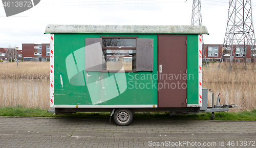 Image of Old green wooden trailer on wheels stands at the side of the roa