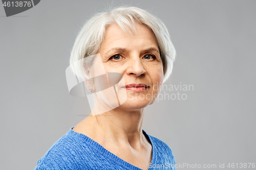 Image of portrait of senior woman in blue sweater over grey