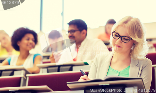 Image of student girl writing to notebook in lecture hall