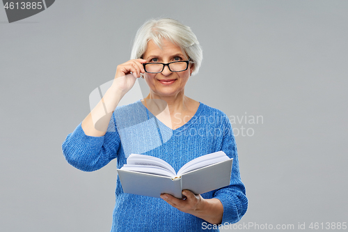 Image of senior woman in glasses reading book