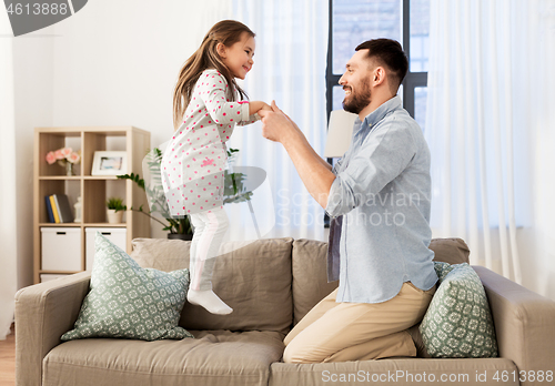 Image of father and daughter jumping and having fun at home