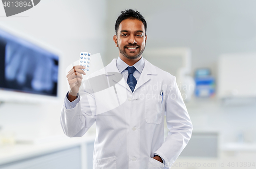 Image of indian male dentist with pills at dental clinic