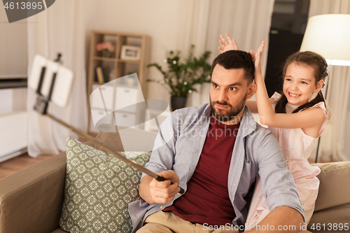 Image of father and daughter taking selfie at home