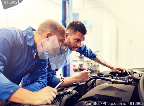 Image of mechanic men with wrench repairing car at workshop