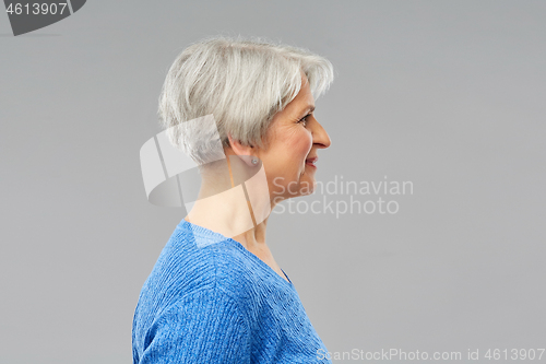 Image of portrait of senior woman in blue sweater over grey