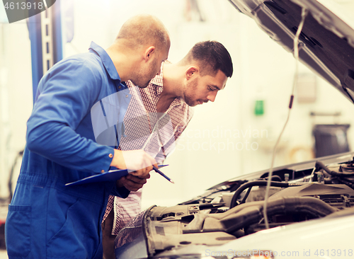 Image of auto mechanic with clipboard and man at car shop