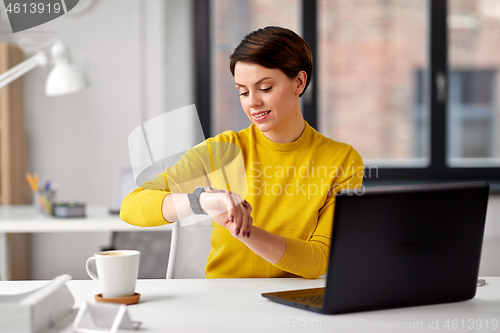 Image of happy businesswoman using smart watch at office