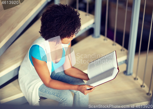 Image of african student girl reading book at library