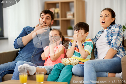 Image of scared family with popcorn watching horror on tv