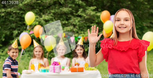 Image of smiling girl waving hand at birthday party in park