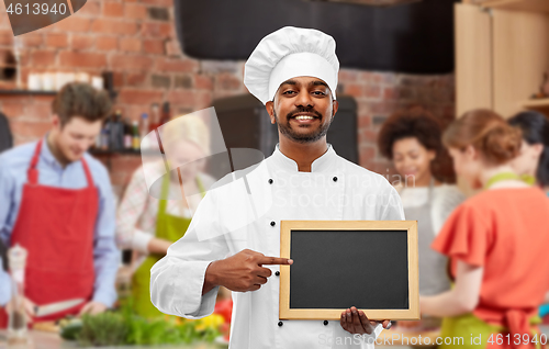 Image of happy indian chef with chalkboard at cooking class