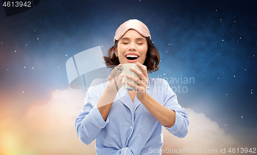 Image of woman in pajama and sleeping mask drinking coffee