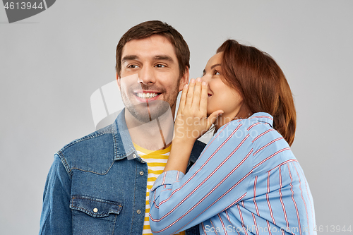 Image of happy couple whispering over grey background