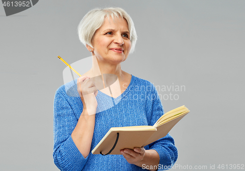 Image of senior woman with pencil and diary or notebook