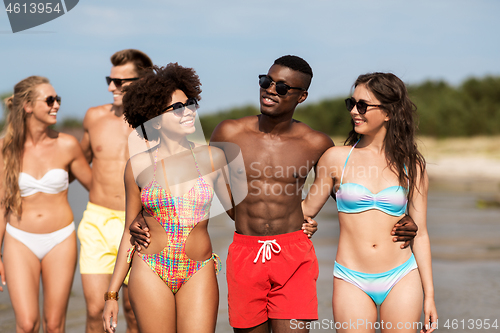 Image of happy friends hugging on summer beach