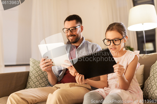 Image of father and daughter with tablet computers at home