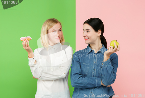 Image of Diet. Dieting concept. Healthy Food. Beautiful Young Women choosing between fruits and unhelathy cake