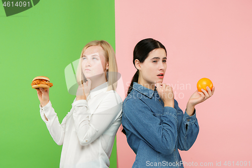 Image of Diet. Dieting concept. Healthy Food. Beautiful Young Women choosing between fruits and unhelathy fast food