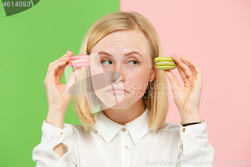 Image of Young beautiful woman holding macaroons pastry in her hands