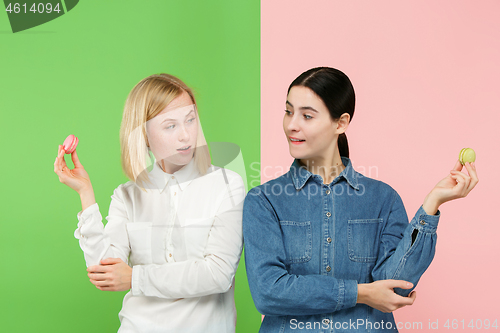 Image of Young beautiful women holding macaroons pastry in her hands