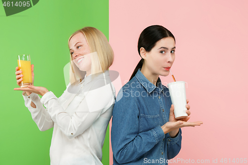 Image of Diet. Dieting concept. Healthy Food. Beautiful Young Women choosing between fruit orange juice and unhelathy carbonated sweet drink