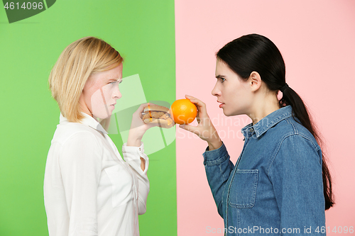 Image of Diet. Dieting concept. Healthy Food. Beautiful Young Women choosing between fruits and unhelathy fast food