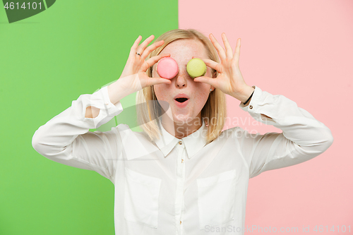 Image of Young beautiful woman holding macaroons pastry in her hands