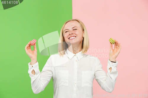 Image of Young beautiful woman holding macaroons pastry in her hands