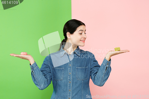 Image of Young beautiful woman holding macaroons pastry in her hands