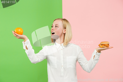 Image of Diet. Dieting concept. Healthy Food. Beautiful Young Woman choosing between fruits and unhelathy fast food