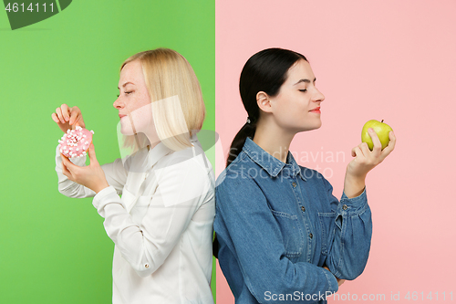 Image of Diet. Dieting concept. Healthy Food. Beautiful Young Women choosing between fruits and unhelathy cake