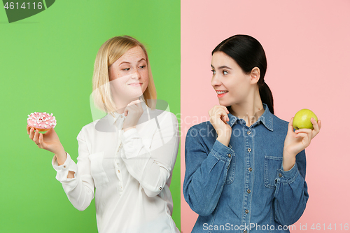 Image of Diet. Dieting concept. Healthy Food. Beautiful Young Women choosing between fruits and unhelathy cake