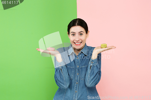 Image of Young beautiful woman holding macaroons pastry in her hands